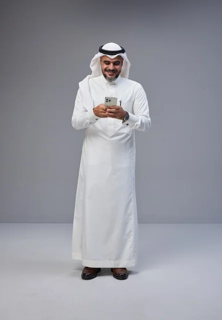 رجل سعودي بالزي التقليدي يستخدم الهاتف الذكي
