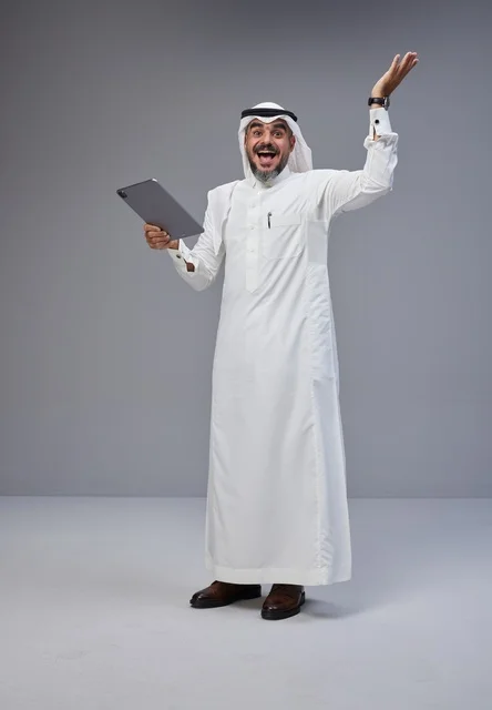 رجل سعودي يحمل جهاز لوحي ويحتفل بالنجاح