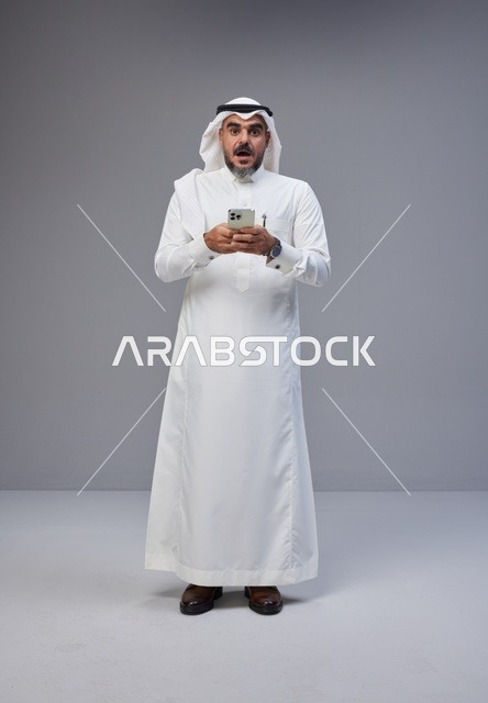 Surprised Saudi Man in Traditional Dress Using Smartphone