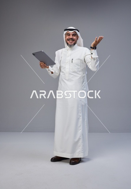 رجل سعودي بالزي التقليدي يستخدم جهازاً لوحياً