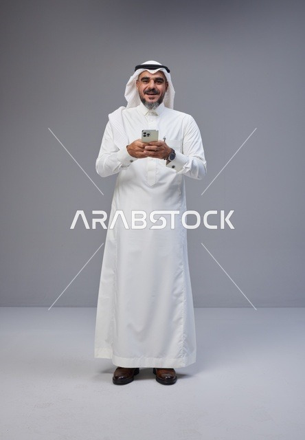 Saudi Man in Traditional Thobe Using Smartphone