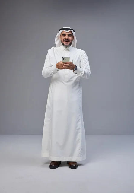 Saudi Man in Traditional Thobe Using Smartphone