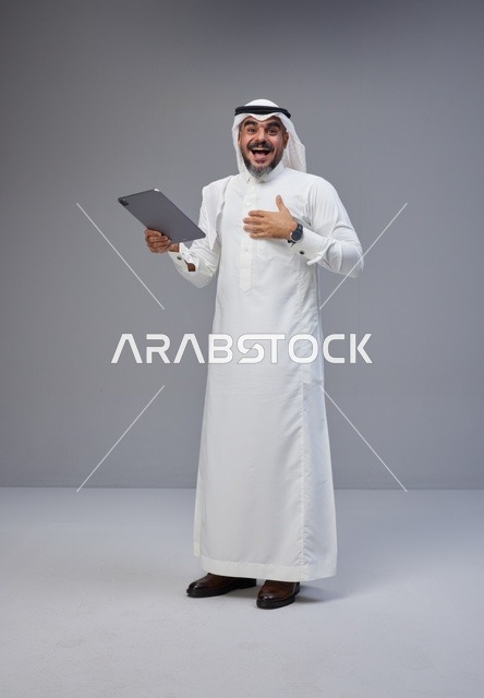 رجل سعودي بالزي التقليدي يستخدم جهاز لوحي في الاستوديو