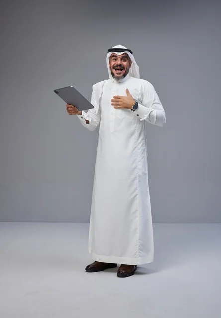 Saudi Man in Traditional Thobe Using Tablet in Studio