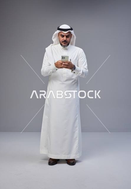 رجل سعودي بالزي التقليدي يستخدم الهاتف الذكي