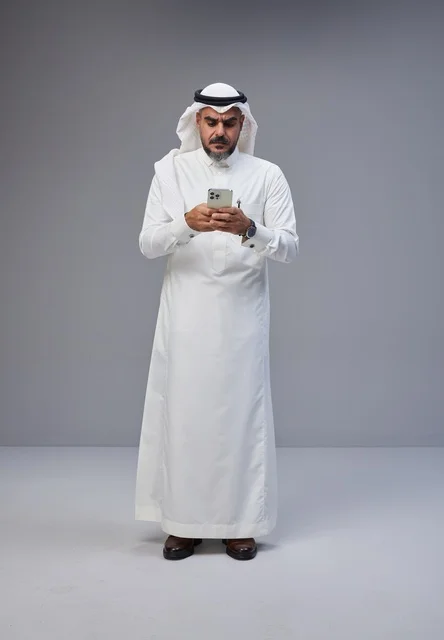 رجل سعودي بالزي التقليدي يستخدم الهاتف الذكي