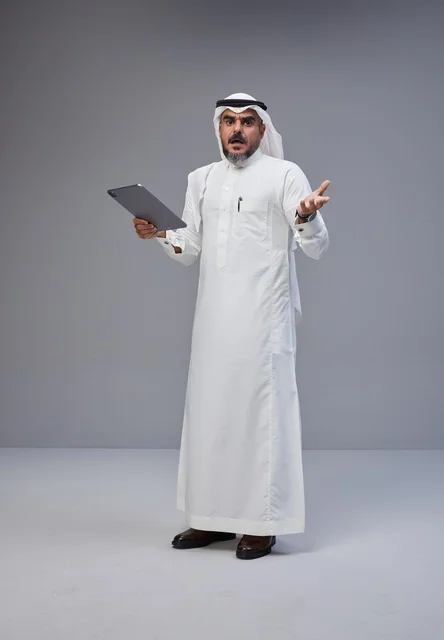 Saudi Man Holding Tablet with Shocked Expression in Studio