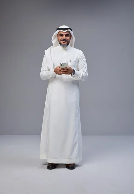 Saudi Man in Traditional Thobe Using Smartphone