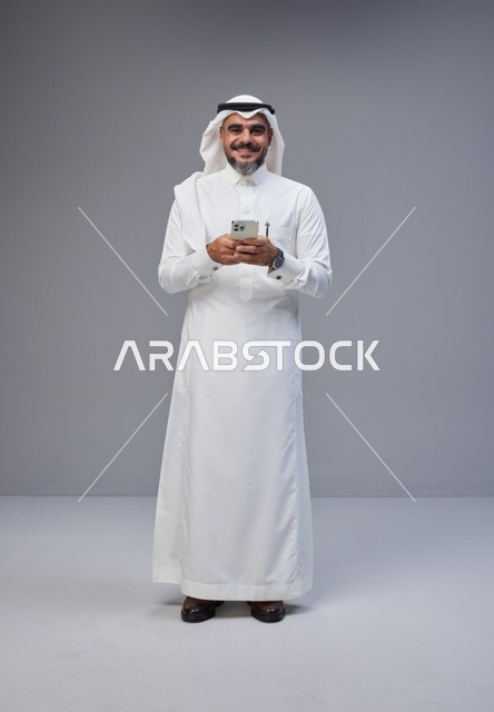 Saudi Man in Traditional Thobe Using Smartphone