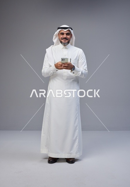 Saudi Man in Traditional Thobe Using Smartphone Studio
