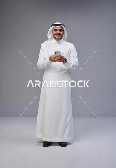Saudi Man in Traditional Thobe Holding Smartphone