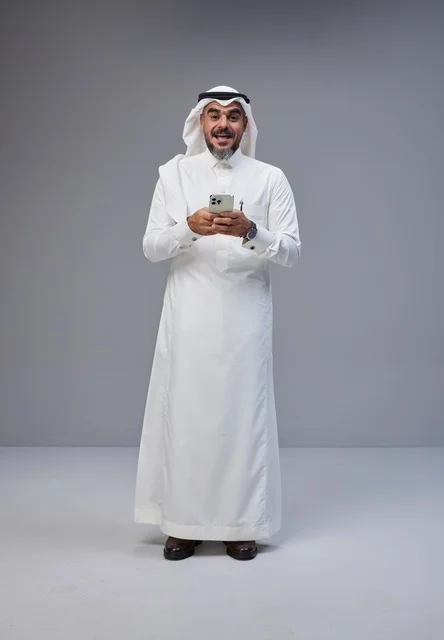 Saudi Man in Traditional Dress Using Smartphone