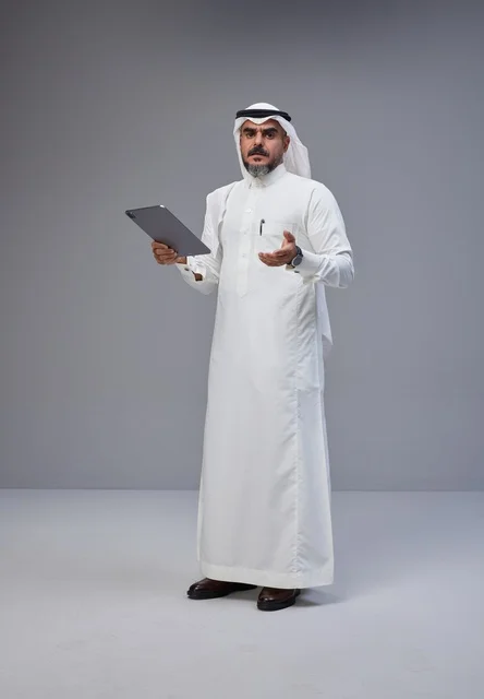 Saudi Man in Traditional Thobe Holding Tablet Studio Shot