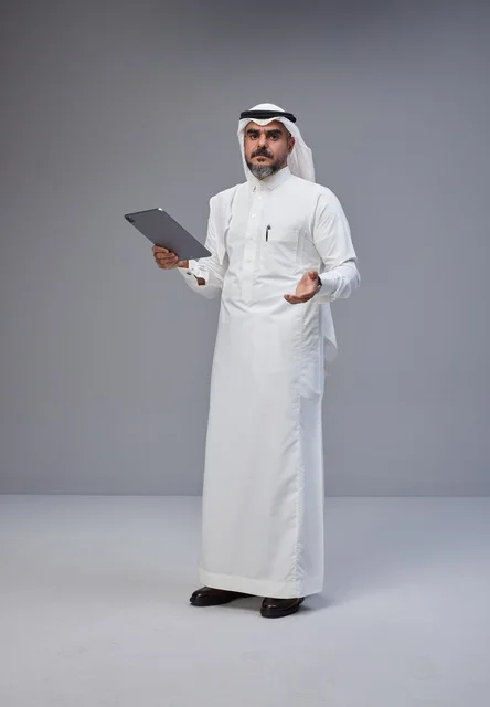 Saudi Man in Traditional Thobe Holding Tablet