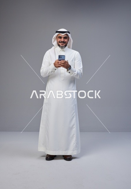 Saudi Man in Traditional Thobe Using Smartphone