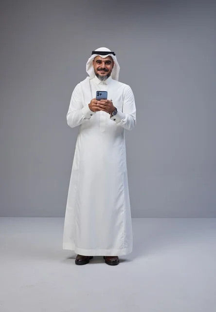 Saudi Man in Traditional Thobe Using Smartphone