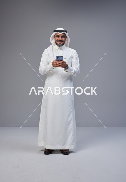 Saudi Man in Traditional Thobe Using Smartphone