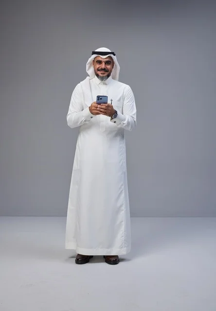 Saudi Man in Traditional Thobe Using Smartphone