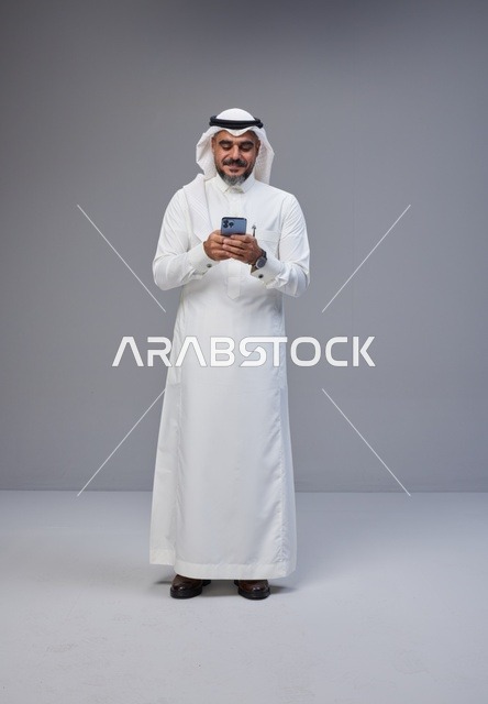 Saudi Man in Traditional Thobe Using Smartphone
