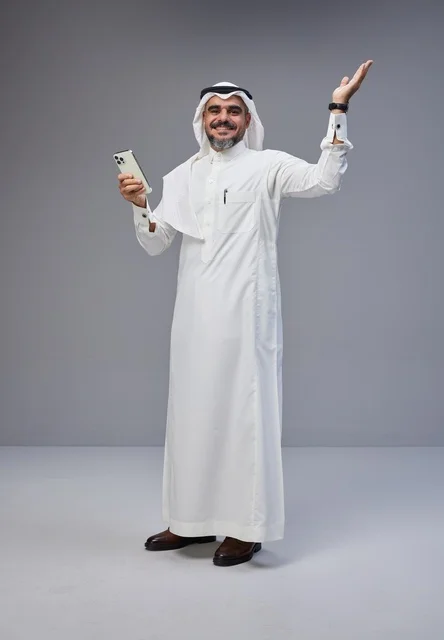 Saudi Man in Traditional Thobe Using Smartphone in Studio