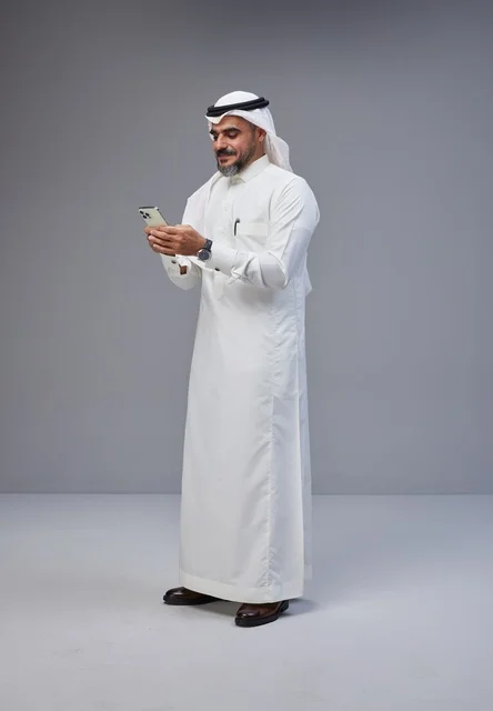 Saudi Man in Traditional Thobe Using Smartphone