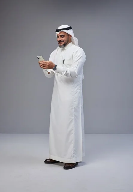 Saudi Man in Traditional Thobe Using Smartphone