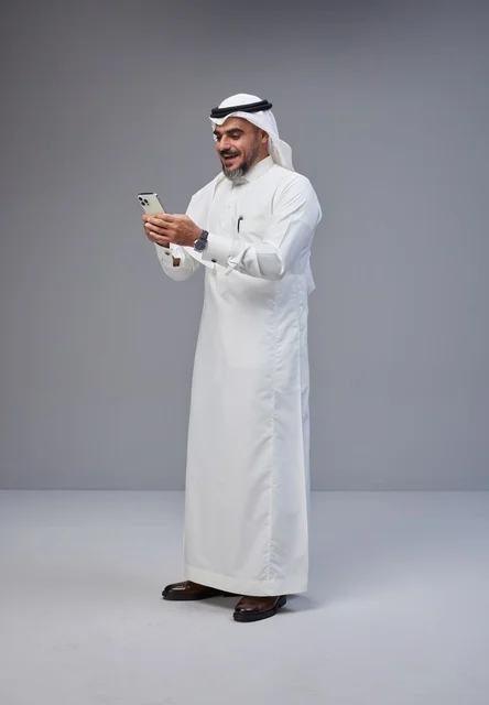 Saudi Man in Traditional Dress Using Smartphone