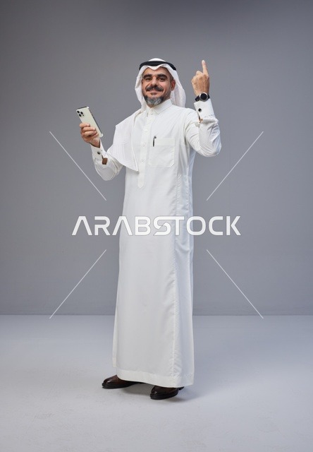 رجل سعودي بالزي التقليدي يستخدم الهاتف الذكي