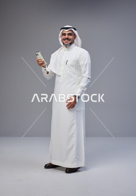 رجل سعودي بالزي التقليدي يستخدم الهاتف الذكي