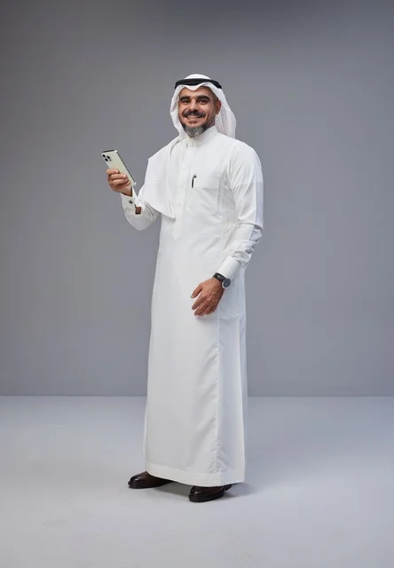 رجل سعودي بالزي التقليدي يستخدم الهاتف الذكي