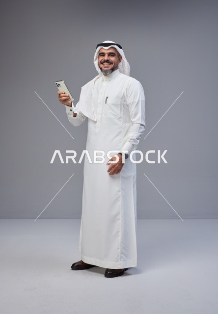 رجل سعودي بالزي التقليدي يستخدم الهاتف الذكي