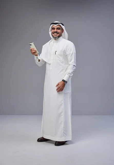 رجل سعودي بالزي التقليدي يستخدم الهاتف الذكي