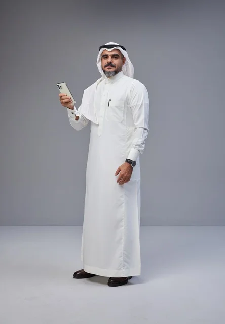 رجل سعودي بالزي التقليدي يستخدم الهاتف الذكي