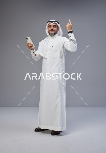 Saudi Man in Traditional Thobe Using Smartphone
