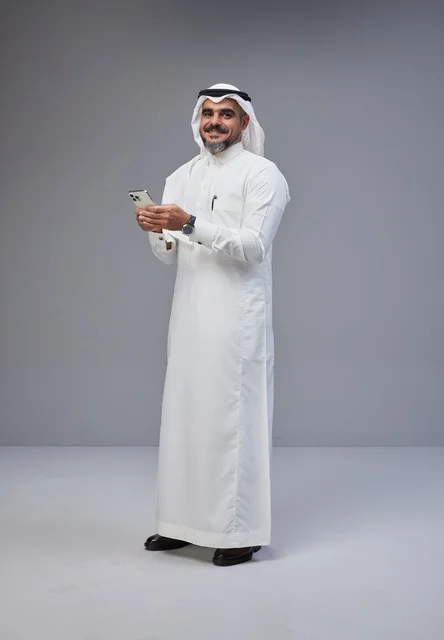 Saudi Man in Traditional Dress Using Smartphone in Studio