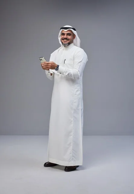 رجل سعودي بالزي التقليدي يستخدم الهاتف الذكي