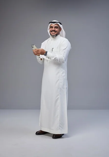 رجل سعودي بالزي التقليدي يستخدم الهاتف الذكي