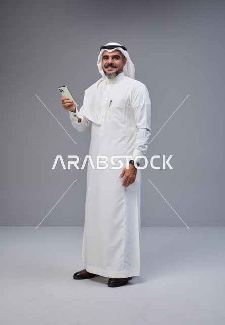 Saudi Man in Traditional Thobe Holding Smartphone
