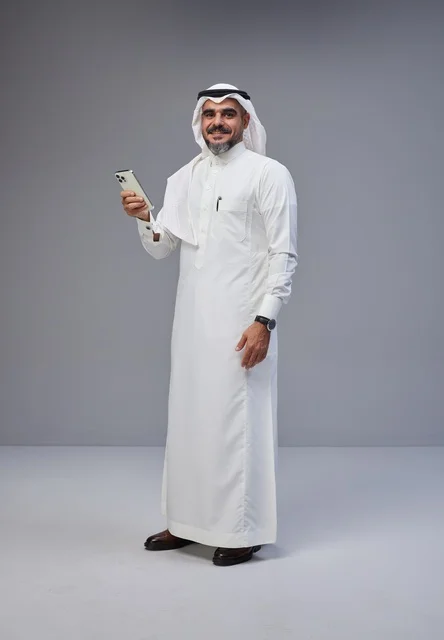 رجل سعودي بالزي التقليدي يستخدم الهاتف الذكي