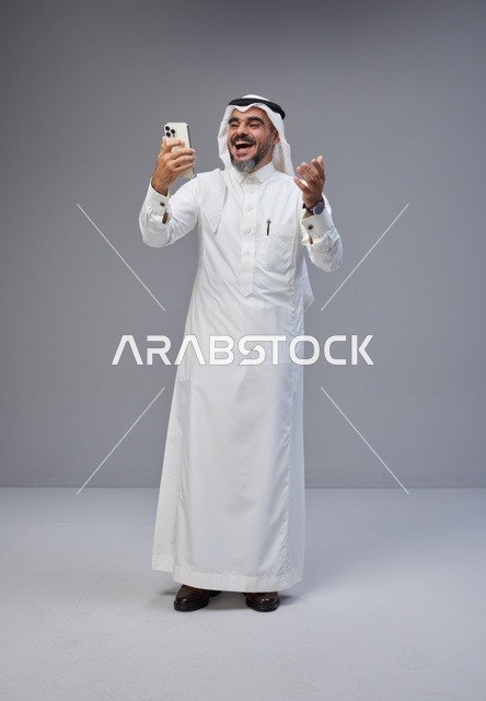 رجل سعودي بالزي التقليدي يستخدم الهاتف الذكي