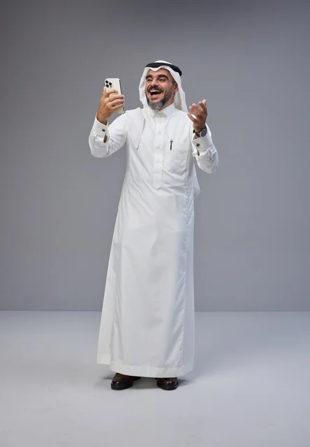 Saudi Man in Traditional Thobe Using Smartphone