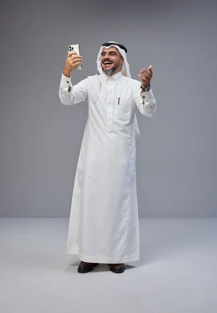 Saudi Man in Traditional Thobe Using Smartphone