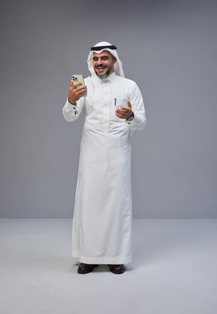 Saudi Man in Traditional Dress Using Smartphone in Studio