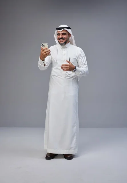 Saudi Man in Traditional Thobe Using Smartphone