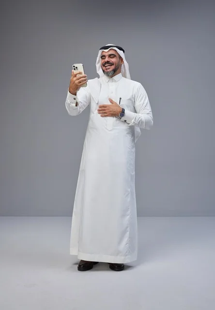 رجل سعودي بالزي التقليدي يستخدم الهاتف الذكي