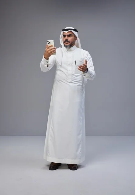 Saudi Man in Traditional Thobe Using Smartphone
