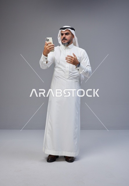 Saudi Man in Traditional Thobe Using Smartphone