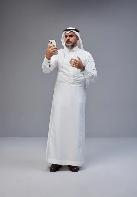 Saudi Man in Traditional Thobe Using Smartphone