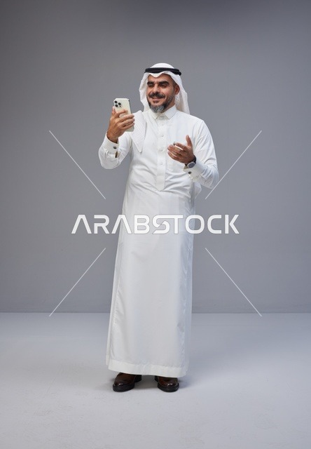 Saudi Man in Traditional Thobe Using Smartphone