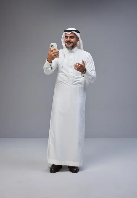 Saudi Man in Traditional Thobe Using Smartphone